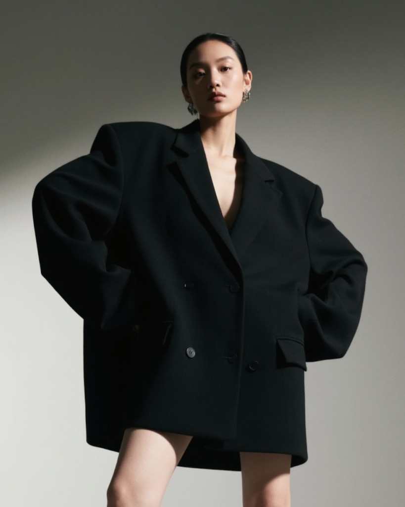 Editorial portrait of a woman in an oversized black coat
